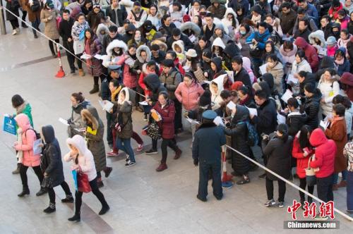 12月10日，山西太原一公务员考点，考生排队准备进入考场。当日，2018年度中央机关及其直属机构公务员招考笔试开考。本次国考共有120多个中央机关及其直属机构和参照公务员法管理的单位参加，计划招录2.8万余人，最终有165.97万人通过报名资格审查，较去年增加了17.34万，通过资格审查人数与录用计划数之比为58：1。 中新社记者 武俊杰 摄